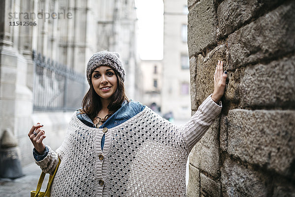 Spanien  Barcelona  Porträt einer lächelnden jungen Frau  die sich an die Wand lehnt
