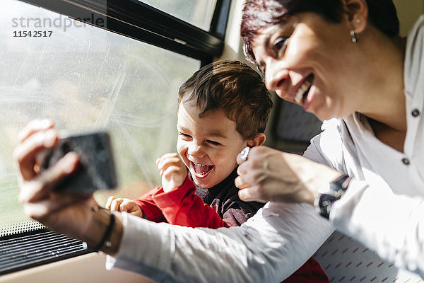 Glücklicher kleiner Junge bei seiner ersten Zugfahrt mit seiner Mutter