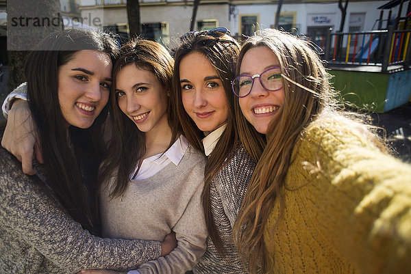 Vier lächelnde junge Frauen  die einen Selfie nehmen.