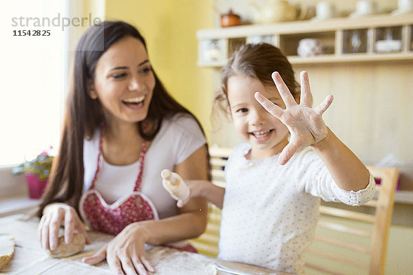 Kleines Mädchen  das seine Hand mit Mehl bedeckt zeigt.