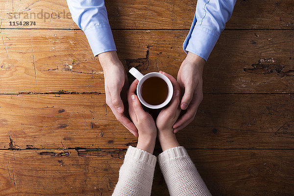 Hände eines jungen Paares mit einer Tasse Tee