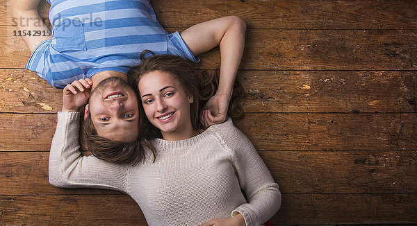 Glückliches junges verliebtes Paar auf Holzboden liegend
