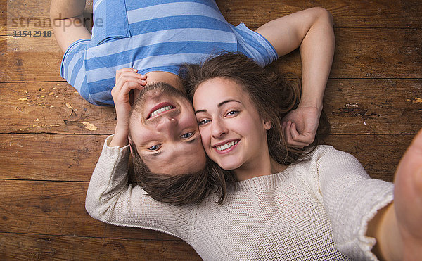 Porträt eines verliebten jungen Paares  Kopf an Kopf auf Holzboden liegend