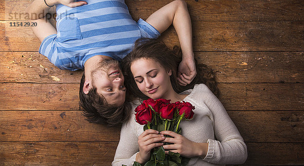 Verliebtes junges Paar auf Holzboden liegend