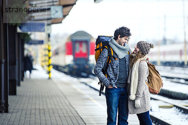 Lächelndes junges Paar auf dem Bahnsteig