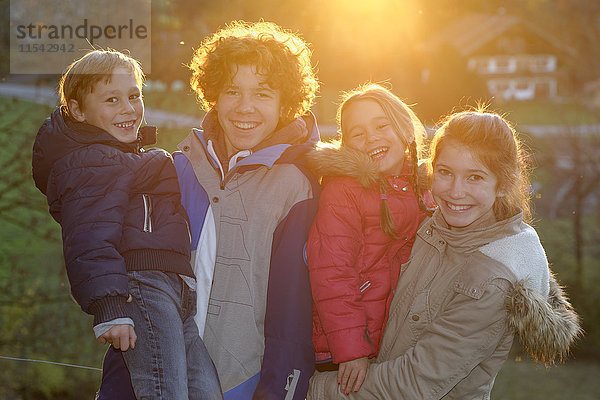 Gruppenbild von vier glücklichen Kindern und Jugendlichen im Gegenlicht