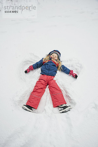 Kleines Mädchen macht einen Schneeengel