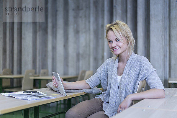 Porträt eines lächelnden Schülers mit digitalem Tablett im Klassenzimmer