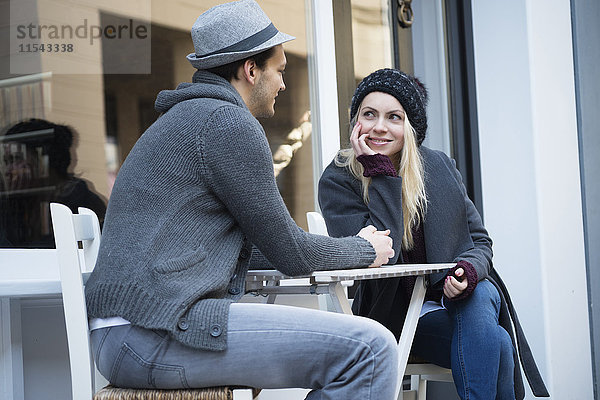 Verliebtes Paar hält sich an den Händen im Straßencafé