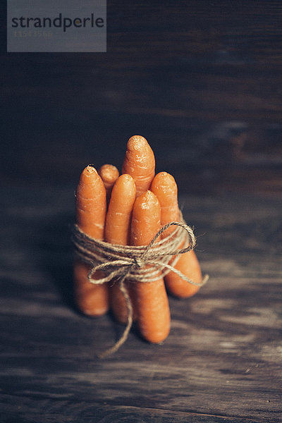 Bund von fünf Karotten auf dunklem Holz