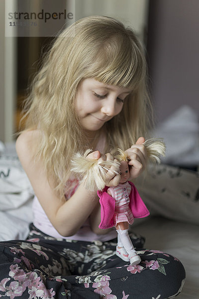 Kleines Mädchen beim Frisieren ihrer Puppe