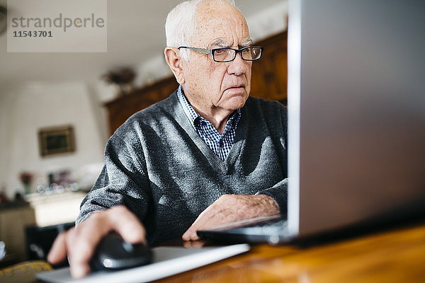 Porträt eines ernsthaft aussehenden älteren Mannes mit Laptop zu Hause