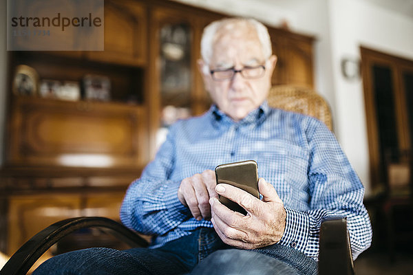 Senior Mann mit Smartphone zu Hause  Nahaufnahme