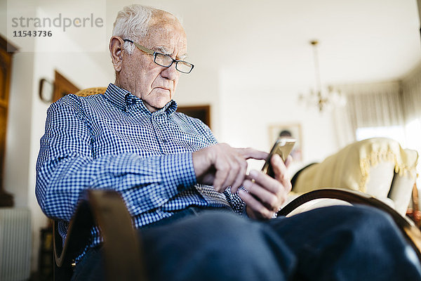 Senior Mann mit Smartphone zu Hause