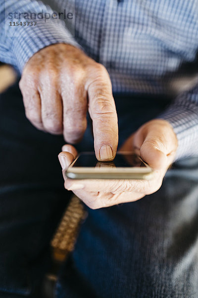 Hände des älteren Mannes mit Smartphone