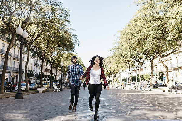 Spanien  Tarragona  glückliches junges Paar  das in der Stadt läuft