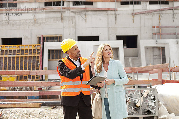 Mann mit Schutzhelm im Gespräch mit Frau auf der Baustelle
