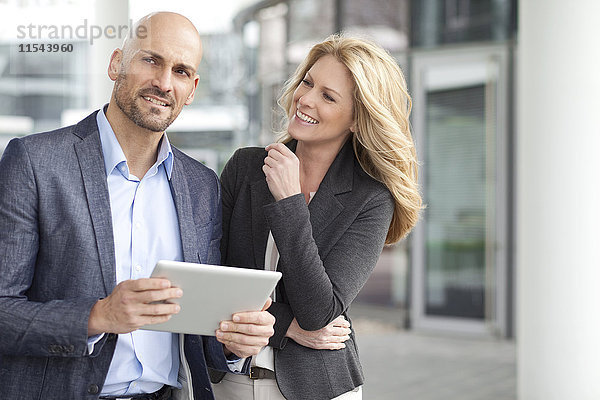 Geschäftsmann und lächelnde Geschäftsfrau mit digitalem Tablett im Freien