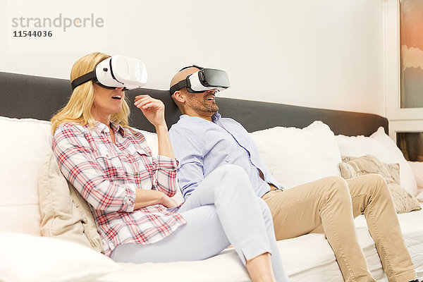 Paar sitzt zu Hause auf der Couch mit Virtual Reality Brille