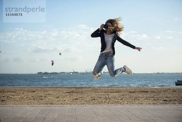 Spanien  Puerto Real  Frau fotografiert beim Springen in der Luft