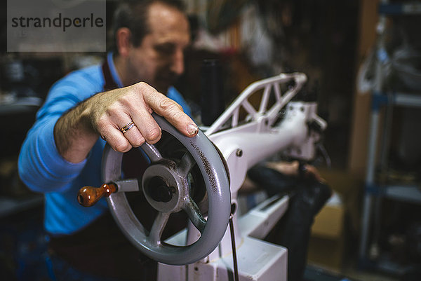 Schuhmacher mit einer Nähmaschine in seiner Werkstatt  Nahaufnahme