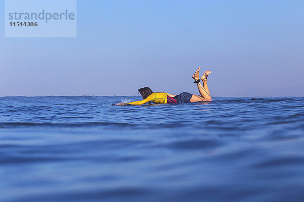 Indonesien  Bali  Frau auf dem Surfbrett liegend im Wasser schwimmend