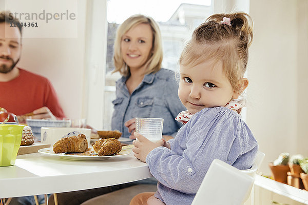 Porträt eines kleinen Mädchens mit einem Glas Milch am Frühstückstisch