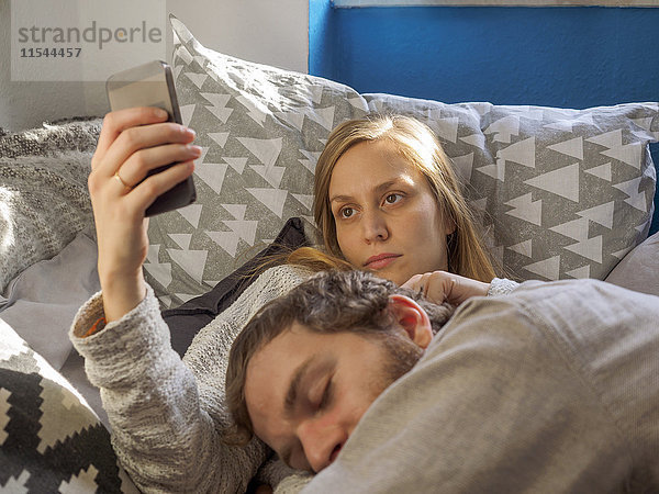 Junges Paar entspannt zu Hause  Frau mit Smartphone