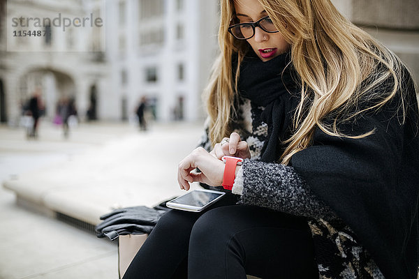 Junge Frau im Freien  die ihre Smartwatch überprüft.