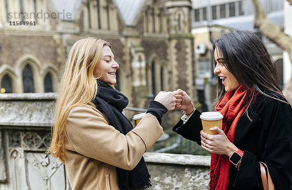 UK  London  Zwei Freunde  die die Stadt erkunden  Kaffee trinken vor der Southwark Cathedral