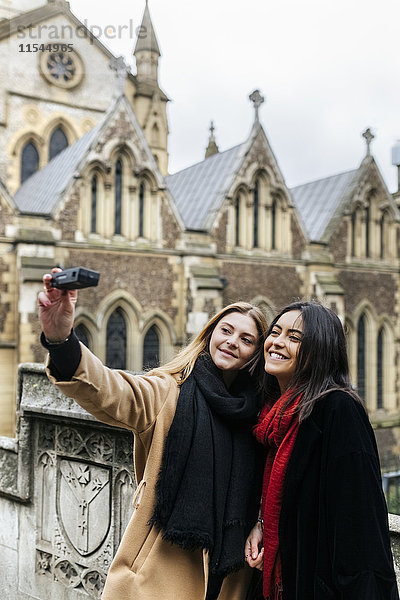 UK  London  Zwei Freunde erkunden die Stadt  fotografieren sich selbst vor der Southwark Cathedral