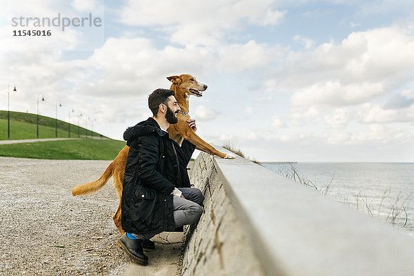 Der Mensch und sein Hund schauen aufs Meer.