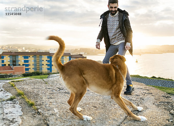 Spanien  Gijon  Mann spielt mit seinem Hund