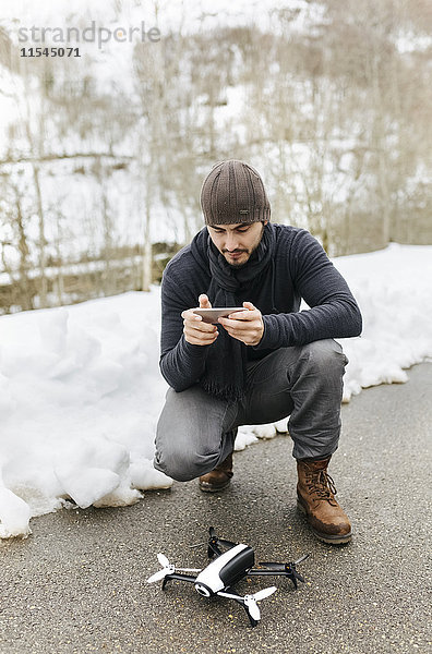Spanien  Asturien  Mann mit Fernsteuerung und Drohne im Winter