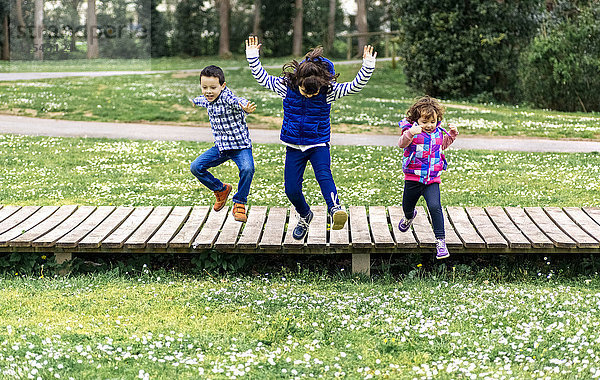 Drei Kinder beim Springen im Park