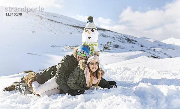Spanien  Asturien  glückliches Paar im Schnee liegend neben Schneemann