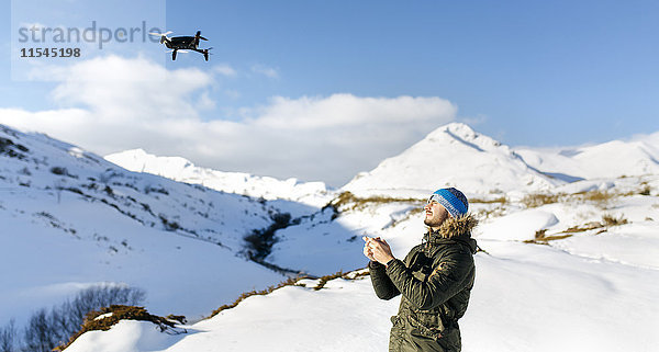 Spanien  Asturien  Mann fliegt Drohne in schneebedeckten Bergen