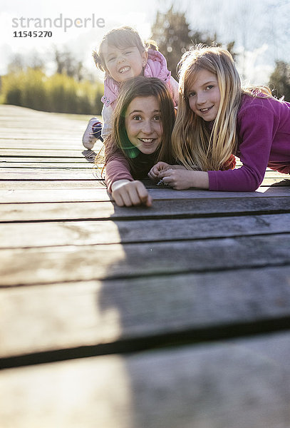 Gruppenbild von drei Mädchen auf einer Strandpromenade mit lustigen Gesichtern