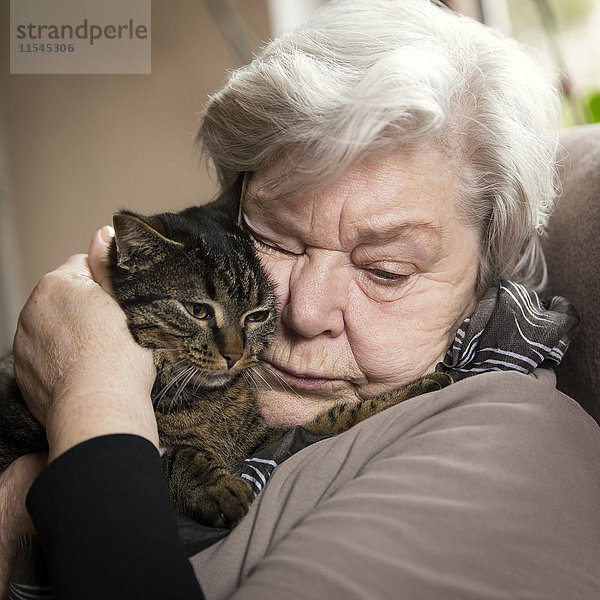 Porträt einer älteren Frau beim Kuscheln mit ihrer Katze