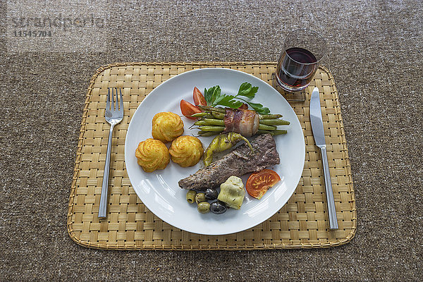 Lammfilet mit Kroketten  grüne Bohnen mit Speck  Artischocke  Tomate und Chilipfeffer  Rotweinglas