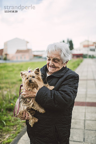 Glückliche Seniorin mit Yorkshire Terrier auf den Armen