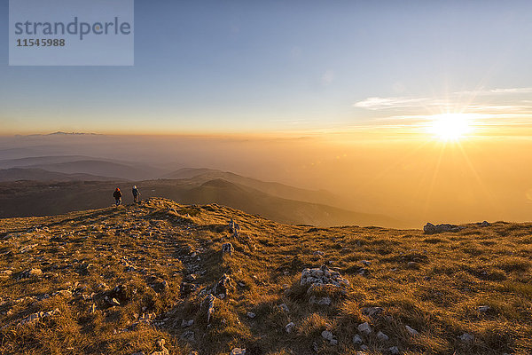 Italien  Marken  Monte San Vicino  zwei Wanderer mit Blick auf den Sonnenuntergang