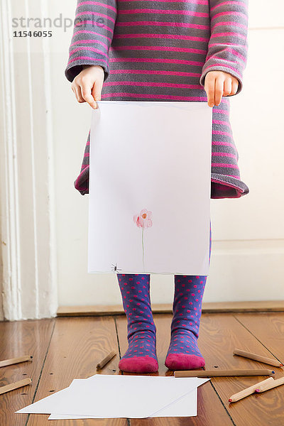 Kleines Mädchen hält ein Blatt Papier mit bemalter Blume.