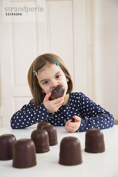 Porträt eines kleinen Mädchens beim Essen von Schoko-Marshmallow