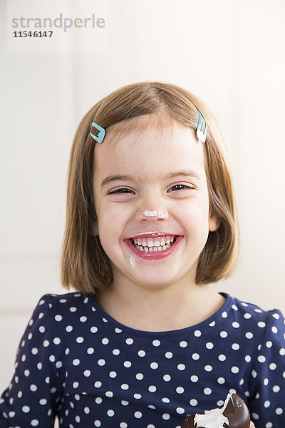 Porträt eines lachenden kleinen Mädchens  das Schoko-Marshmallow isst.
