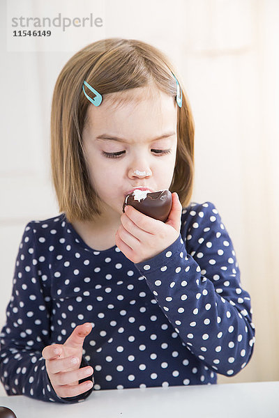 Porträt eines kleinen Mädchens beim Essen von Schoko-Marshmallow