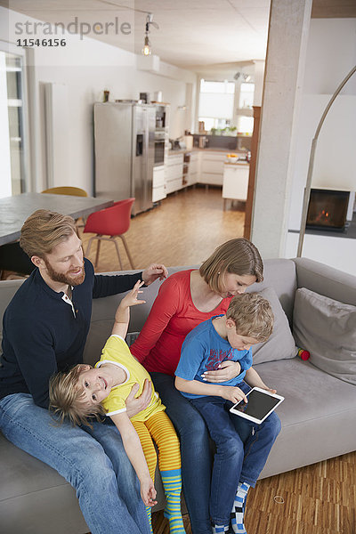 Vierköpfige Familie mit digitalem Tablett auf der Couch