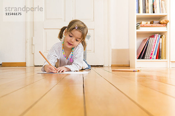 Porträt eines lächelnden kleinen Mädchens auf Holzbodenmalerei mit Buntstiften