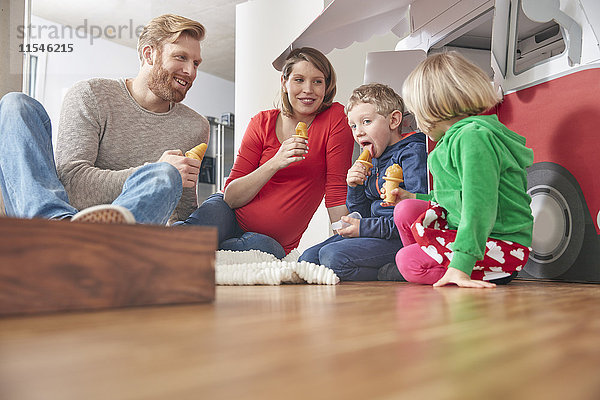 Glückliche Familie mit Eis am Stiel und Modellauto im Wohnzimmer