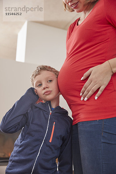 Junge hört auf den Bauch der schwangeren Mutter